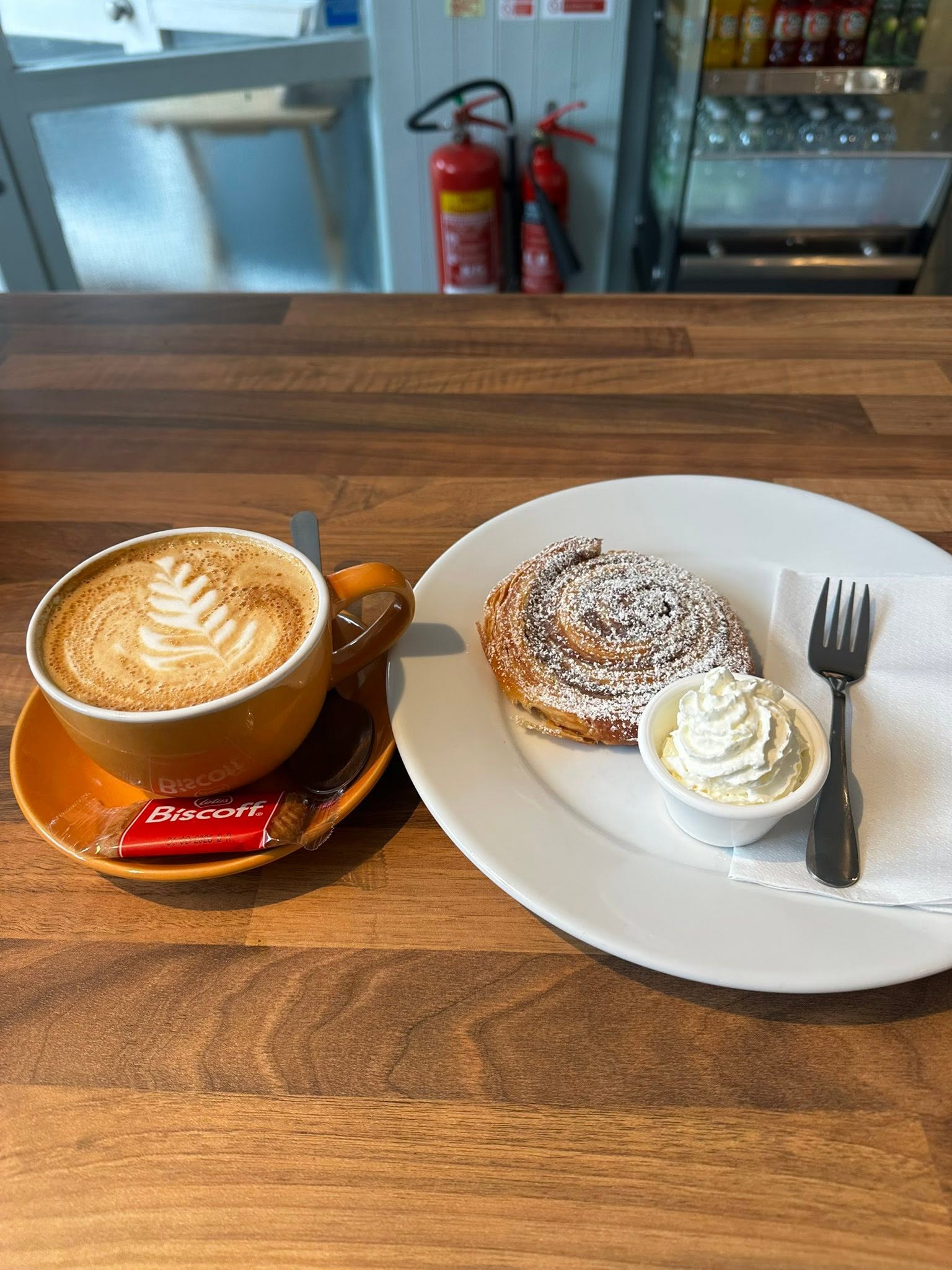 Cappuccino with latte art next to a fresh pastry