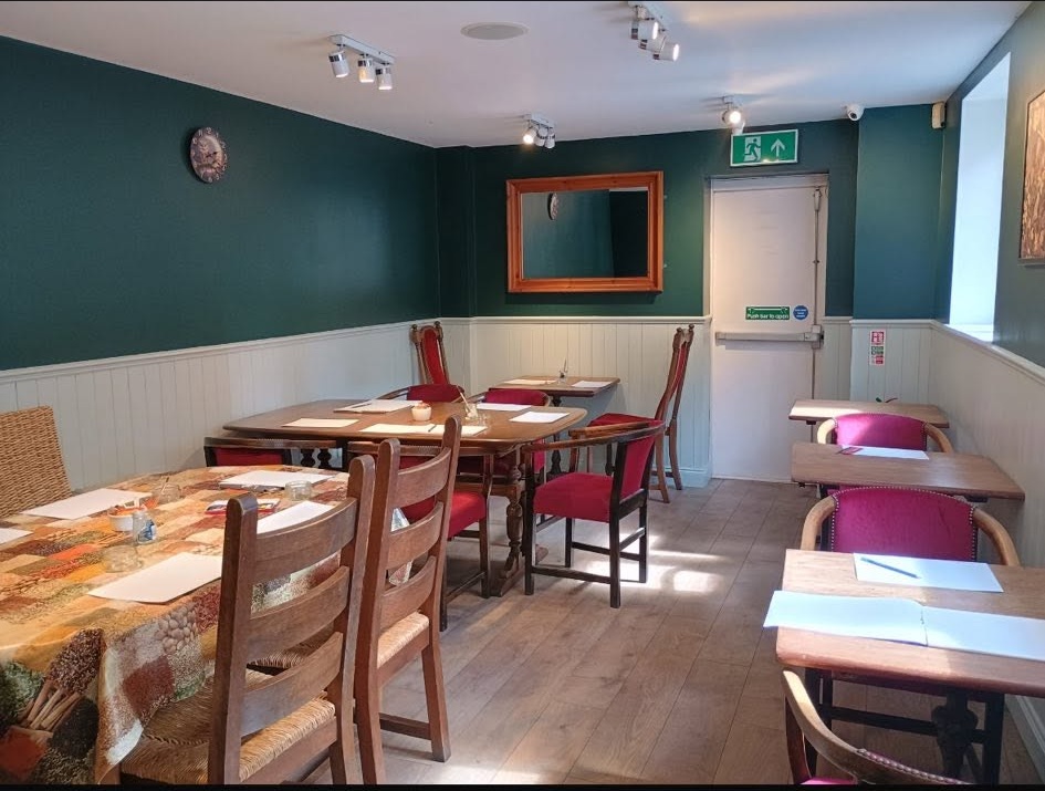 Inside the coffeehouse — dining tables and chairs against green wainscoted walls